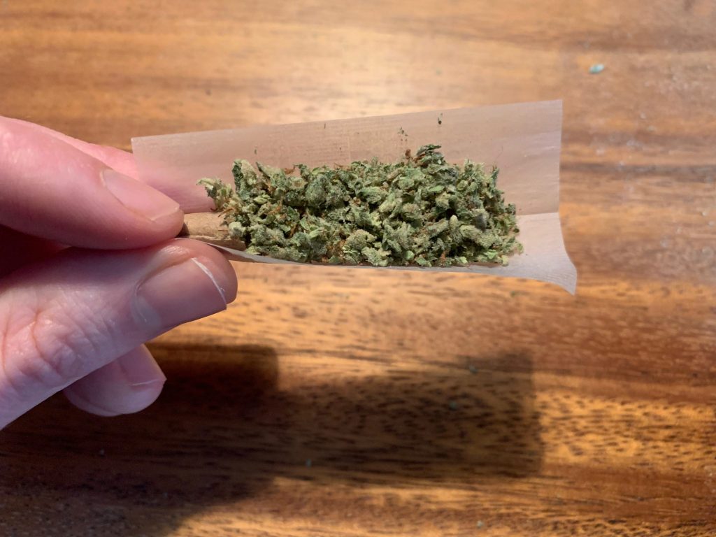 a paper with weed sitting in it being held